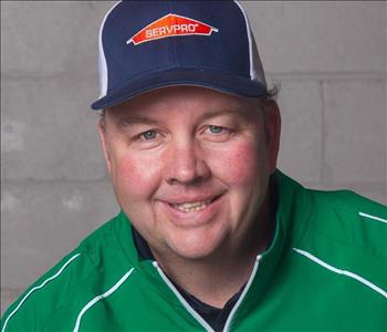 man in green jacket and baseball hat smiling