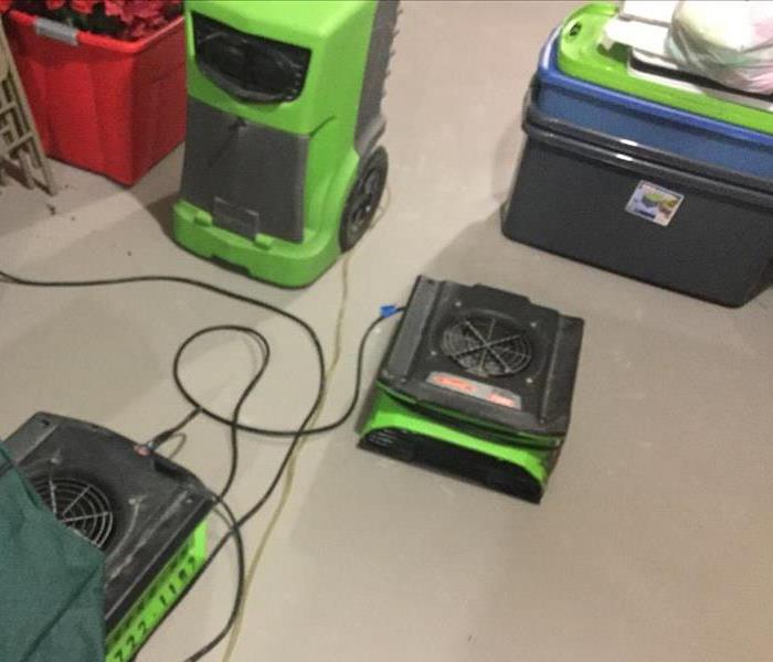 commercial facility with water damaged floors. Green air movers and a green dehumidifier are working to dry the area